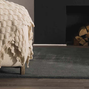 Living room scene with a charcoal Brockton Solid Night Blue Wool Rug, fireplace, and cozy blanket. Roomscene-Rectangle