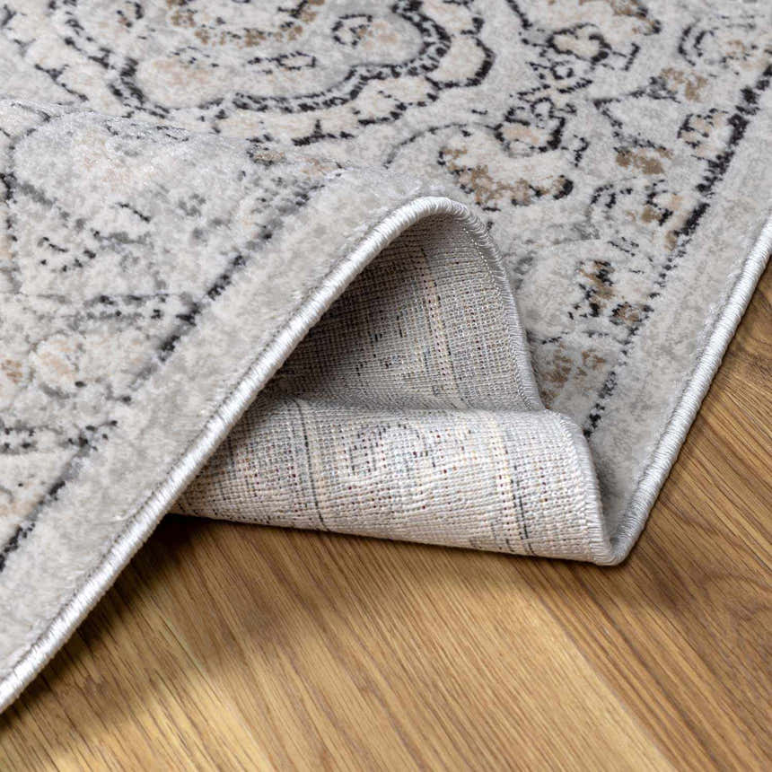 Close-up of the New Parkerfield Area Rug, showing its beige, black, and gray traditional vintage pattern and machine-woven construction. Fold