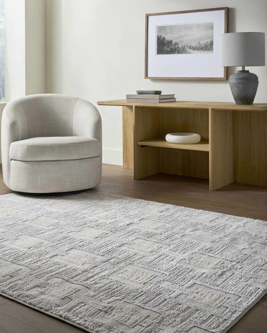 Living room scene with a cream chair and the cream and gray Jackie Area Rug. Roomscene-Rectangle