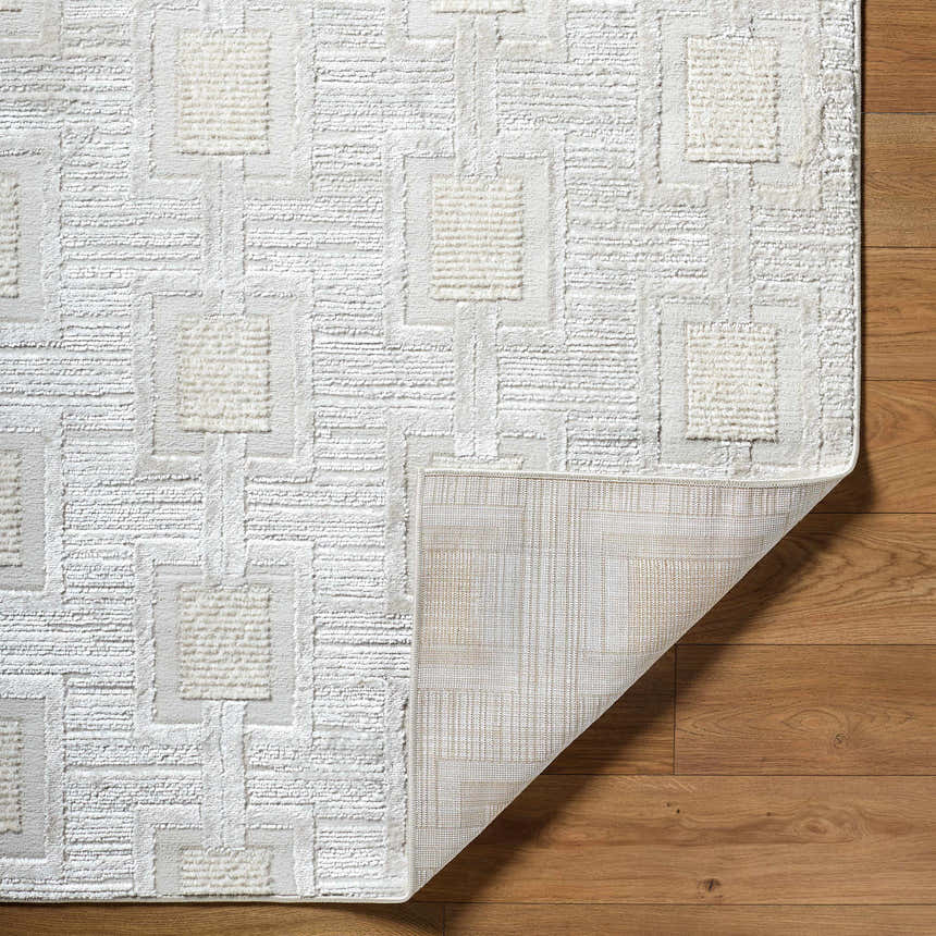 Close-up of the Jackie Area Rug featuring a cream, ivory, and white geometric pattern and machine woven texture. Fold