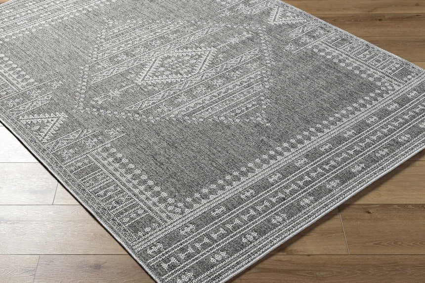 Close-up of the gray and white Asuman Area Rug showing its traditional geometric pattern and woven texture. Corner