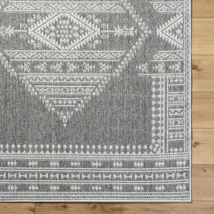 Close-up of the gray and white Asuman Area Rug showing its woven texture and traditional geometric pattern. Corner