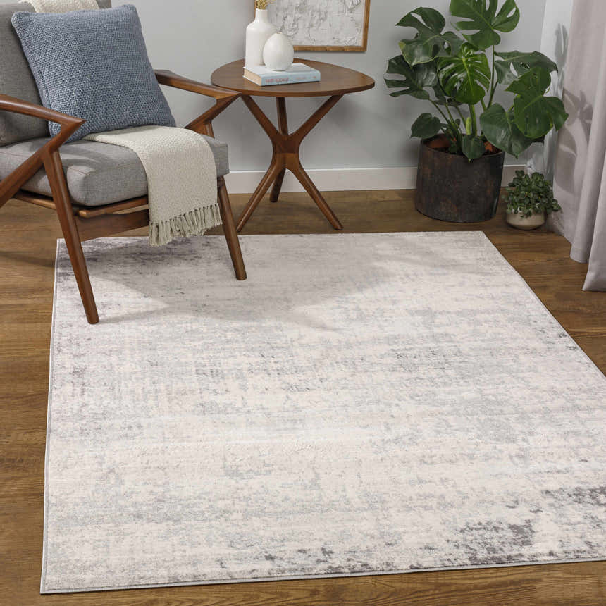 Living room scene with a Kalanganan Abstract Gray Rug, chair, side table, and plant. Neutral tones create a calm, contemporary mood. Roomscene-Rectangle