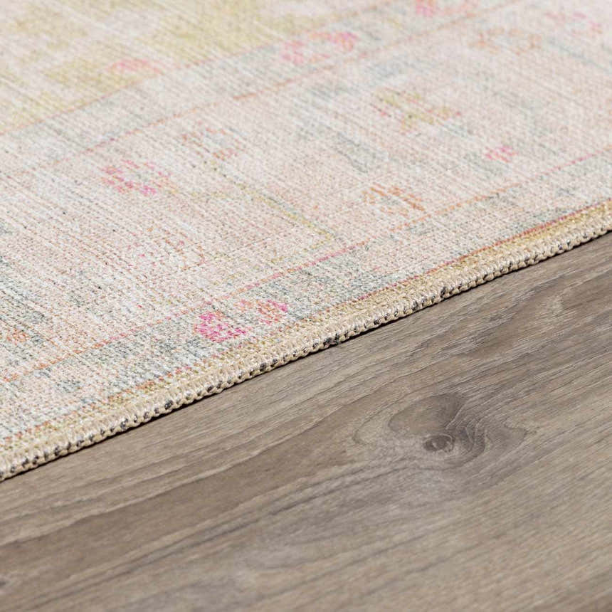 Close-up of the Bozkurt Boutique Washable Rug showing its Persian-style design, pink, green, and beige colors, and woven texture. Corner