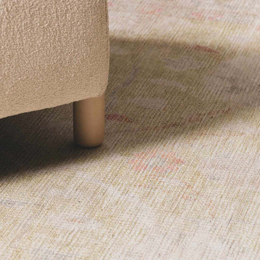Close-up of the Bozkurt Boutique Washable Rug showing its texture and muted colors next to a sofa leg. Roomscene-Rectangle