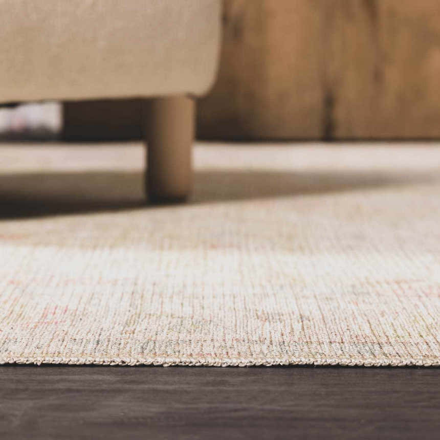 Close-up of the neutral-toned Bozkurt Boutique Washable Rug with subtle pattern and texture, under a beige sofa. Roomscene-Rectangle