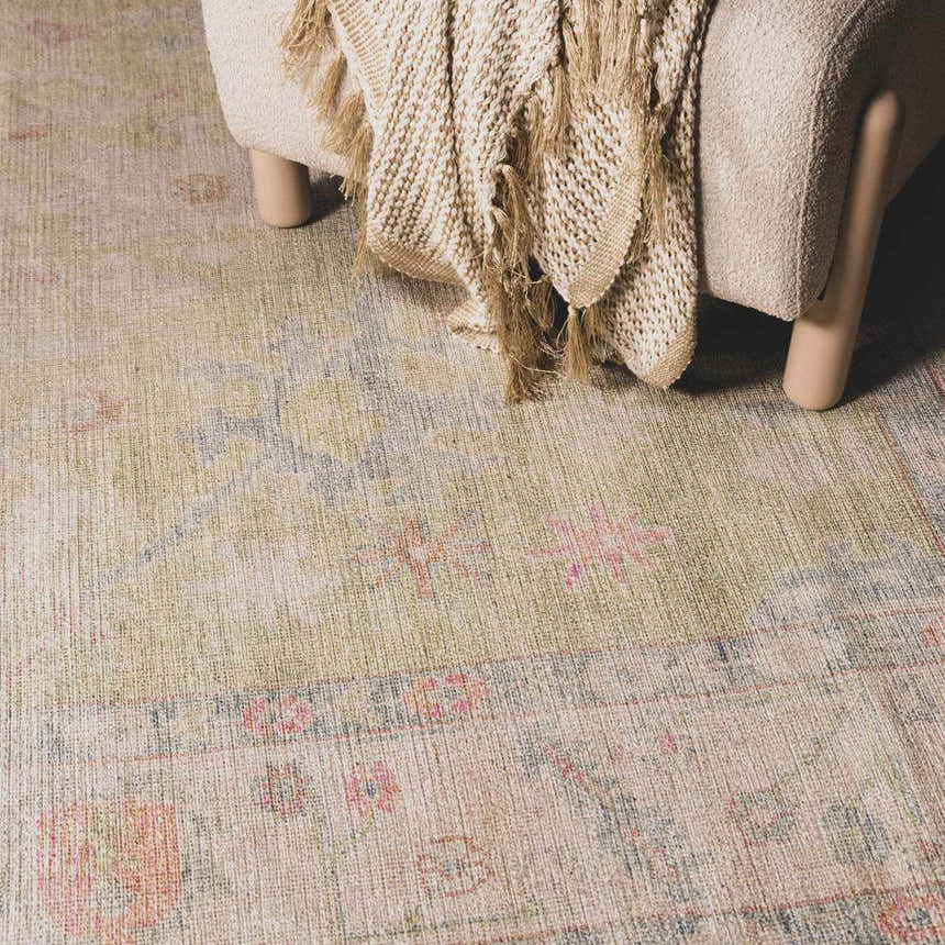 Close-up of the Bozkurt Boutique Washable Rug in cloud gray, lambswool, and pink floral accents next to a chair. Roomscene-Rectangle