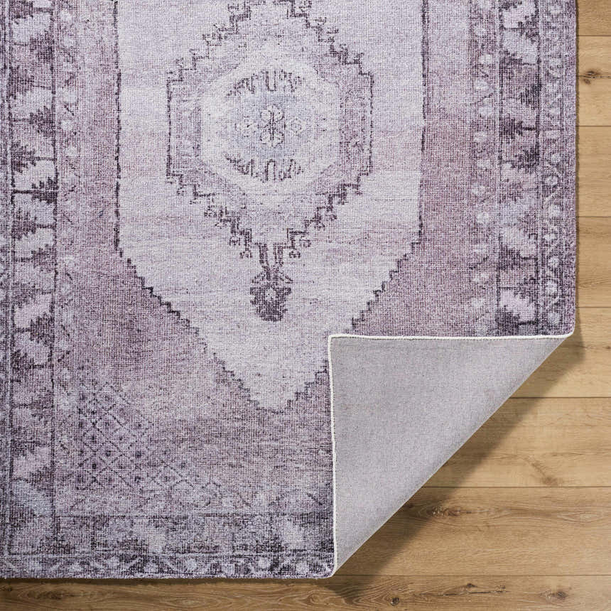 Close-up of the hand-tufted Wayde Area Rug. Traditional design in dusty rose, lavender, and mauve on a wood floor. Fold