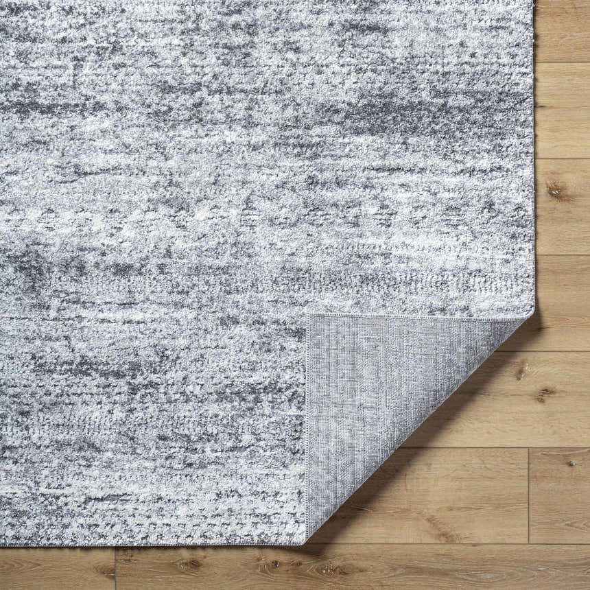 Close-up of the Kohaku Black Area Rug showing its black, charcoal, and light gray abstract pattern and woven texture. Fold