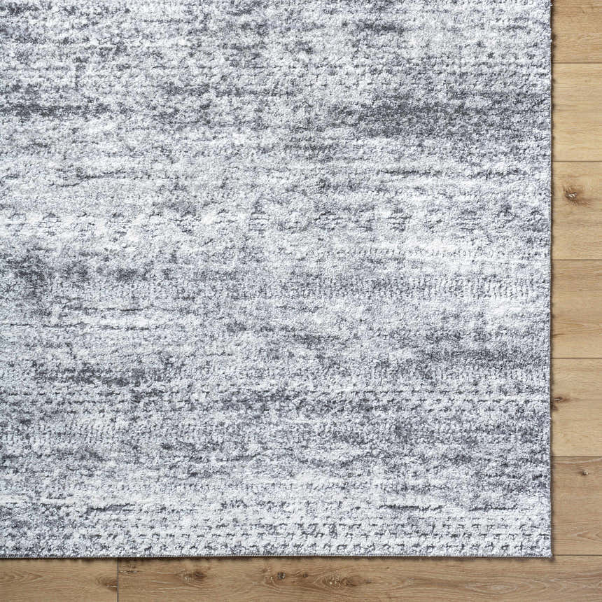 Close-up of the Kohaku Black Area Rug showing its charcoal, light gray, and black textured pattern. Corner