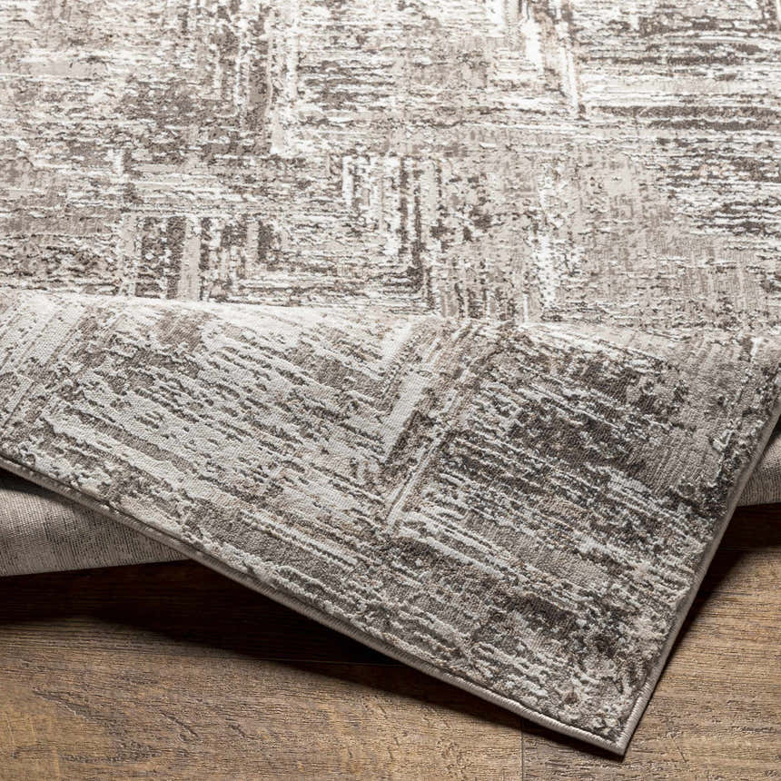 Close-up of the Kutloanong Area Rug showing its charcoal, gray, and ivory abstract pattern and soft texture. Fold