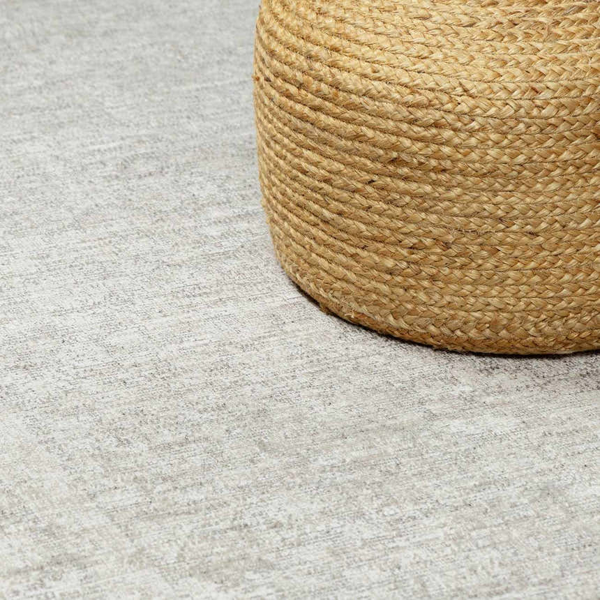 Close-up of the ivory Livabliss x Galey Alix Maria Elena V Vintage Medallion Area Rug with a tan jute pouf. Styleshot