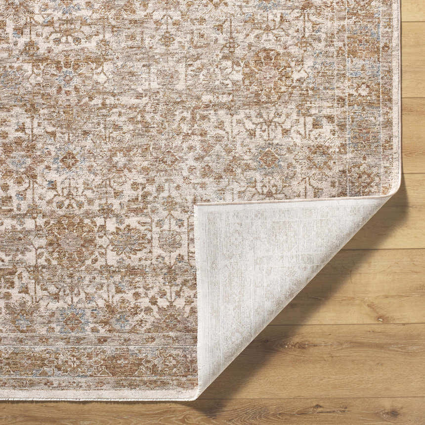 Close-up of the Andres Sage Area Rug showing the traditional light brown, cream, and blue floral pattern and machine-woven texture. Fold