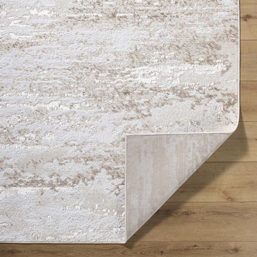 Close-up of Arenda Tan Area Rug showing cream and tan abstract pattern and texture on wooden floor. Fold