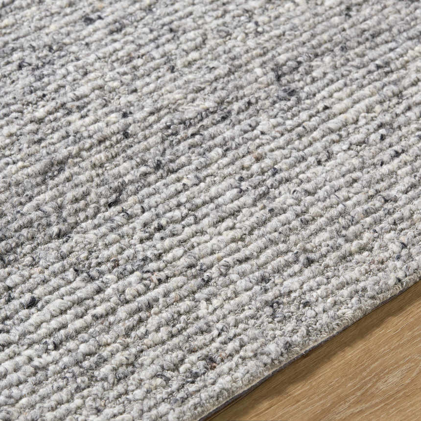 Close-up of the hand-tufted Winta Charcoal Wool Area Rug, showing its gray, ash, and silver gray tones and textured wool design. Texture
