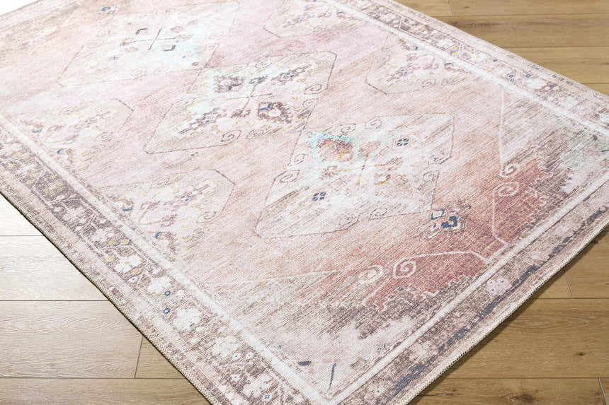 Close-up of Ussun Washable Area Rug. Farmhouse style rug in beige, brown, and dusty pink on wood floor. Corner