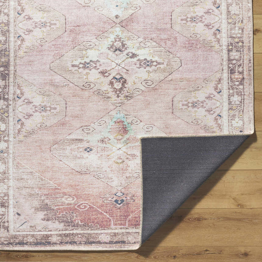 Close-up of the Ussun Washable Area Rug showing its dusty pink, beige, and brown traditional pattern and non-slip backing. Fold