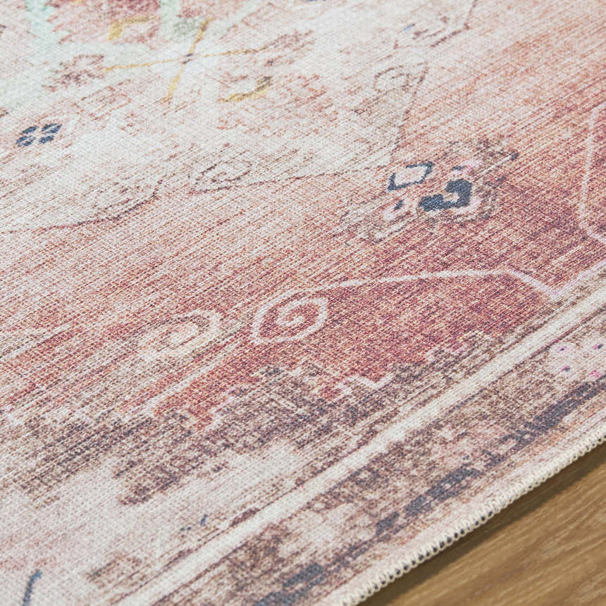 Close up of the Ussun Washable Area Rug showing beige, rust, and black traditional pattern and woven texture. Texture