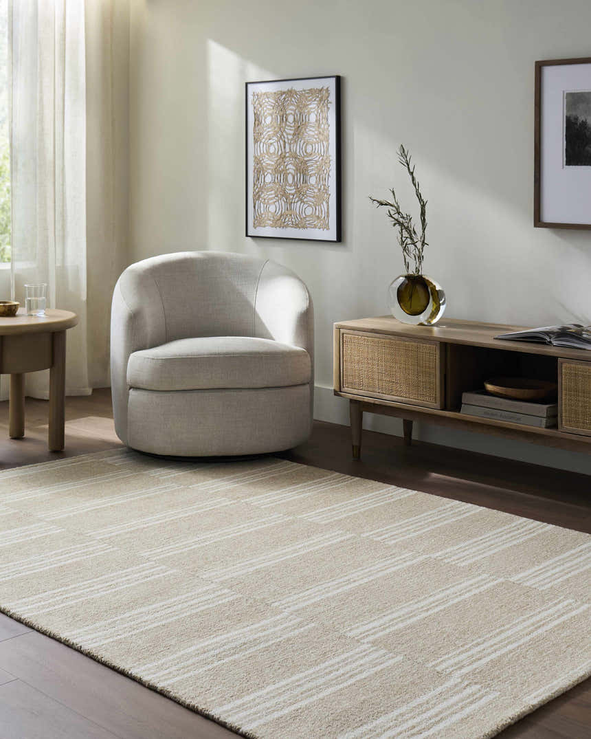 Living room scene with beige Argyro Area Rug, ivory chair, and sandstone-toned furniture. Warm, transitional style. Roomscene-Rectangle