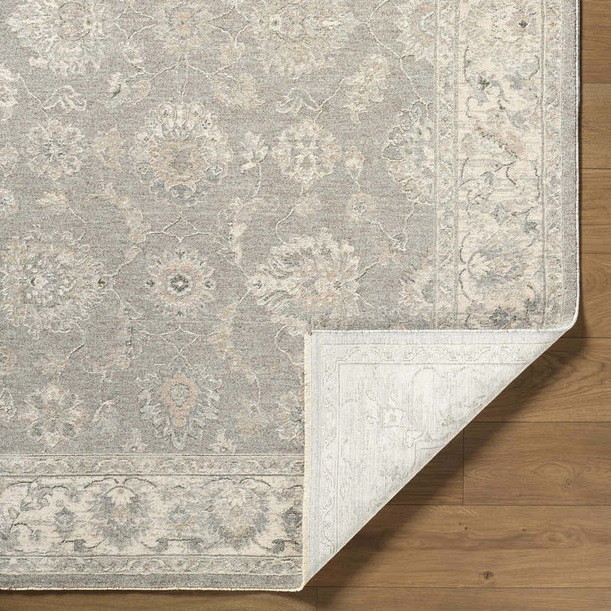 Close up of the Alinae Area Rug showing a traditional floral pattern in cream, green, and slate blue on hardwood floors. Fold
