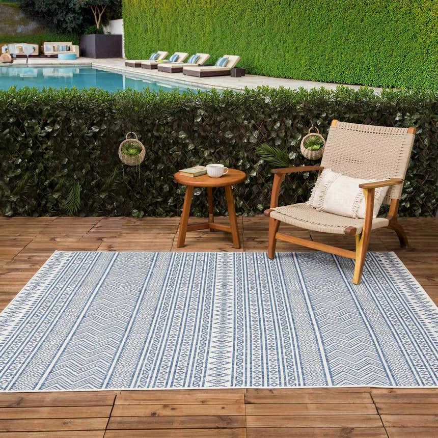 Outdoor patio scene with Madras Light Blue Green rug, wooden furniture, pool, and green hedge. Roomscene-Rectangle
