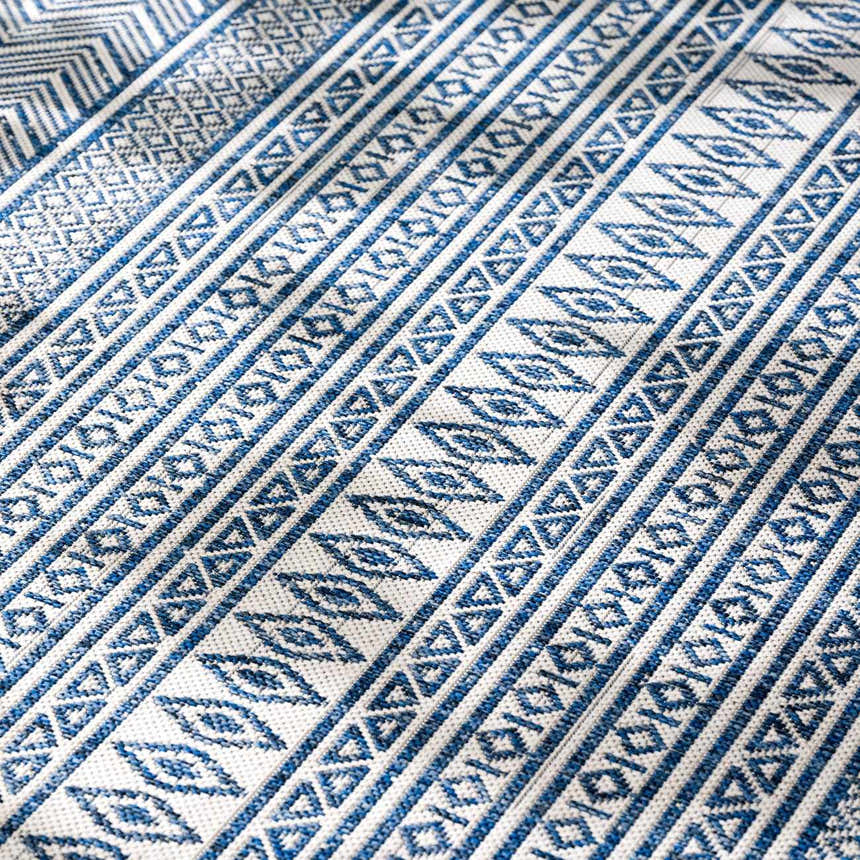 Close-up of the Madras Light Blue Green All Over Performance Area Rug featuring a blue and white geometric pattern. Texture