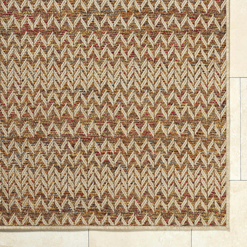 Close-up of Alazne Burnt Orange Area Rug showing woven texture and geometric chevron pattern in orange, cream, and terracotta. Corner