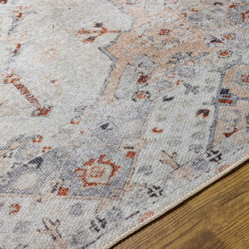 Close-up of Midtown Washable Area Rug. Brick red, charcoal, and gray oriental rug pattern on a wood floor. Texture