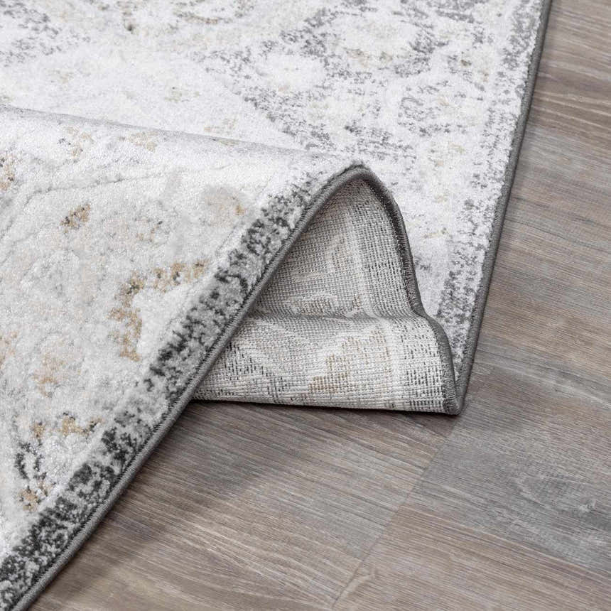 Close-up of the Minoa Area Rug showing its beige, gray, and charcoal distressed pattern and woven texture. Fold