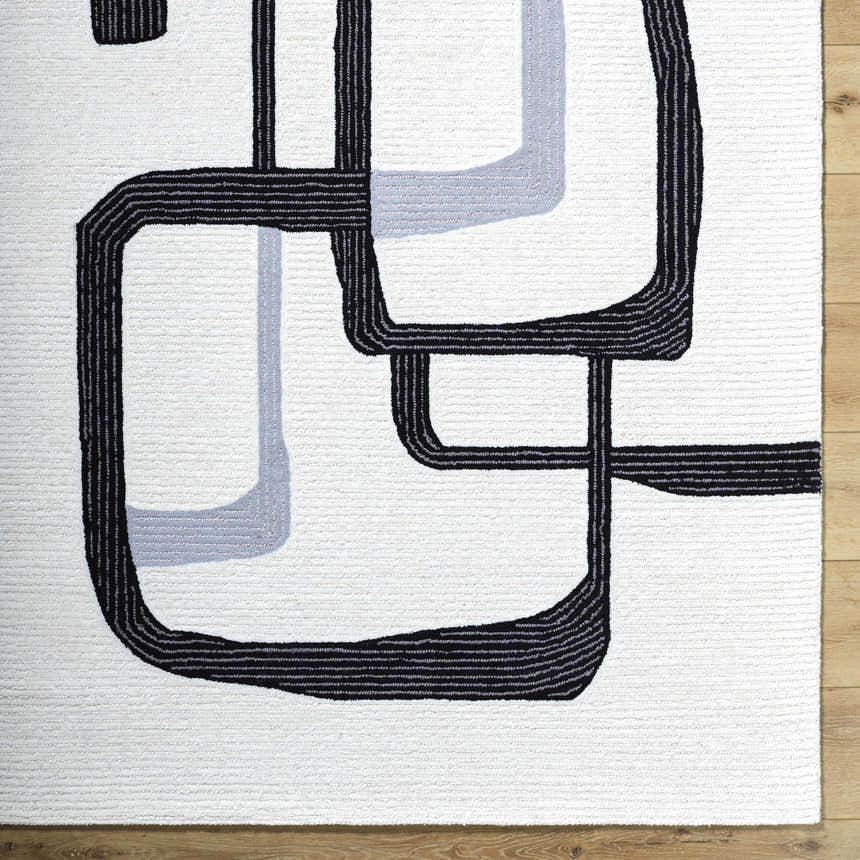 Close up of the Ulfah Area Rug. Hand tufted wool rug with a geometric design in ash and jet black. Corner