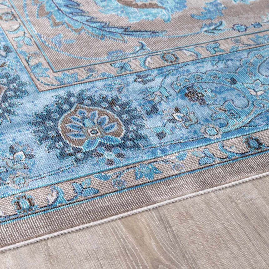 Close-up of the Mardina Turquoise Area Rug showing its beige and blue traditional vintage pattern and machine-woven texture. Pile