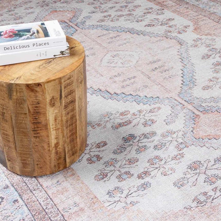 Close-up of the Moora Washable Area Rug showing its traditional, floral pattern and soft aqua, blush, and brown colors. Styleshot