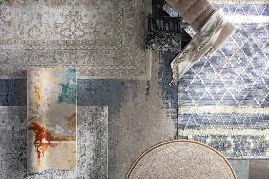 Overhead shot of assorted Stock Area Rug - Clearance rugs in charcoal, beige, and blue tones. Styleshot