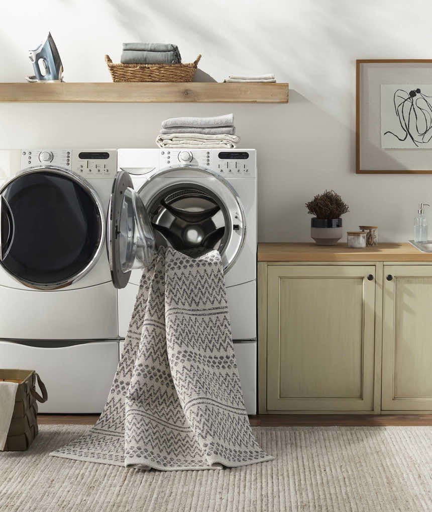 Laundry room scene with gray and white Nalcrest Washable Area Rug being washed in a front load washing machine. Washing-Machine