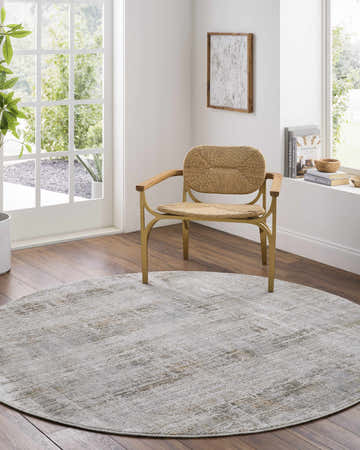 Sunlit room with a round Neron Blue Gray Thick Luxe Abstract Rug, woven chair, and wood floors. Roomscene-Round