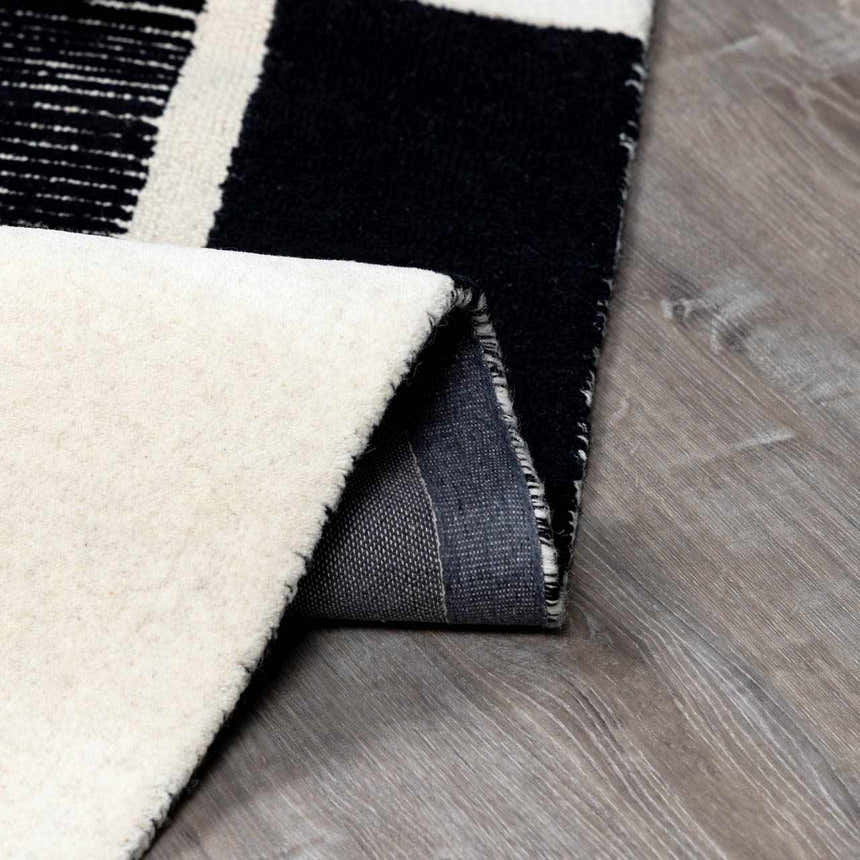 Close-up of the black and cream Brooklyn Modern hand-tufted wool area rug showing texture and backing. Fold