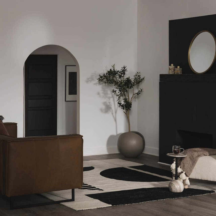 Living room scene with a Brooklyn Modern hand tufted wool area rug in black and cream, paired with a brown leather chair. Roomscene-Rectangle
