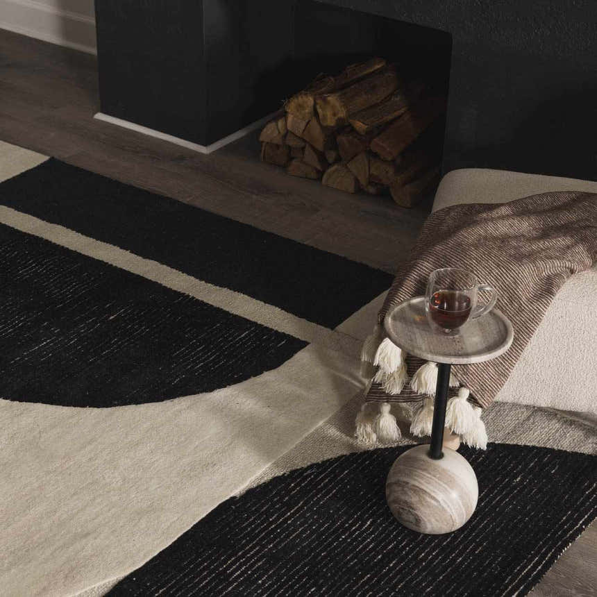 Living room scene with black fireplace, wood pile, and Brooklyn Modern hand tufted wool area rug in black and cream. Styleshot