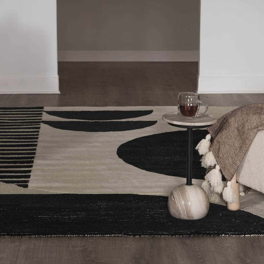 Living room detail with black and cream Brooklyn Modern hand tufted wool area rug, side table, and blanket. Styleshot