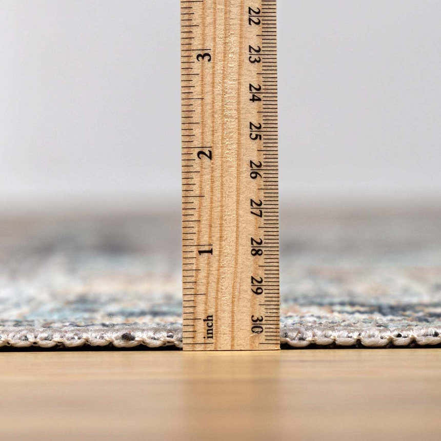 Close-up of Green Nisa Tumble Dry Washable Rug thickness, showing the rug's pile height with a ruler. Pile