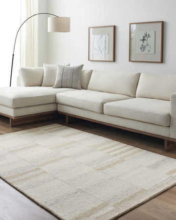 Living room scene with a Max Handmade Becki Owens x LIVABLISS rug in cream and tan under a cream sectional sofa. Roomscene-Rectangle
