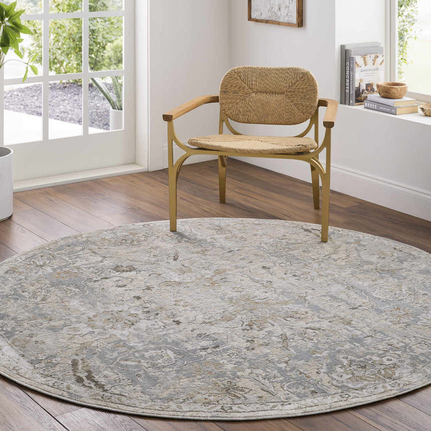 Sunlit room scene with a round Nasir Thick Luxe Boutique Rug in charcoal, cream, and gray under a woven chair. Roomscene-Round