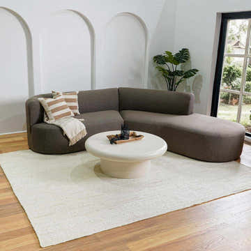 Living room with a cream Pangnir Braided Jute Rug, gray sectional sofa, and round coffee table. Coastal Grandmother style. Roomscene-Rectangle