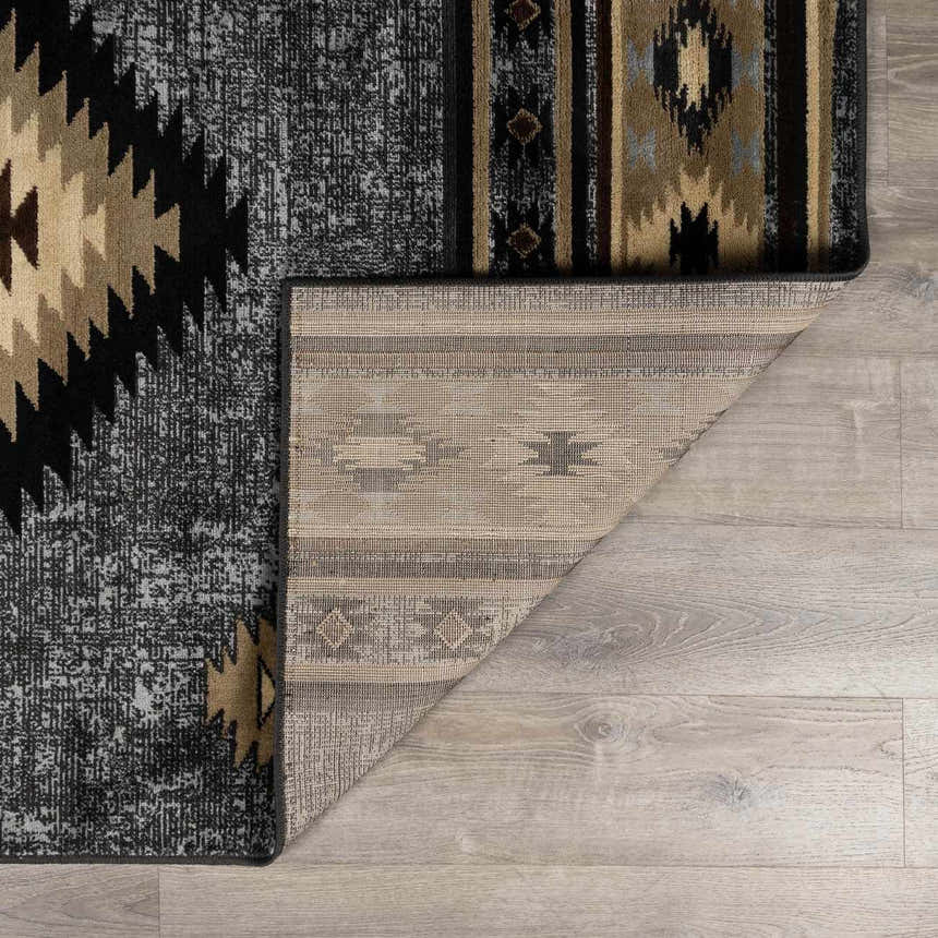 Close-up of the Buckhaven Area Rug showing its Southwestern pattern, black, tan, and gray colors, and machine-woven texture. Fold