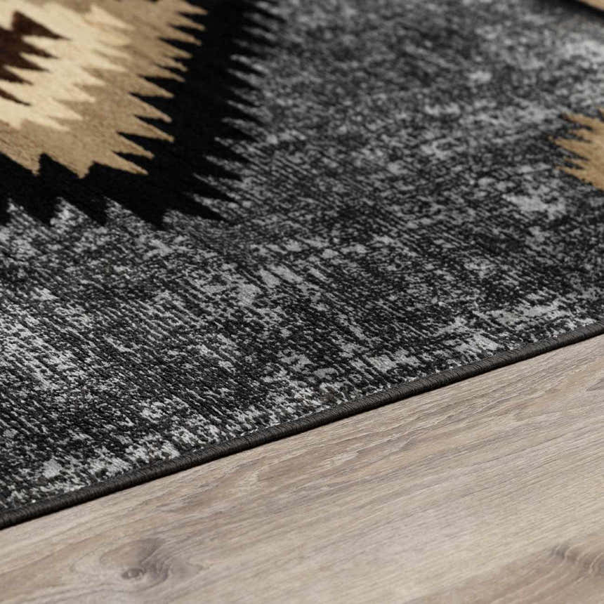Close-up of the Buckhaven area rug showing its black, gray, and tan Southwestern-inspired pattern and textured weave. Corner