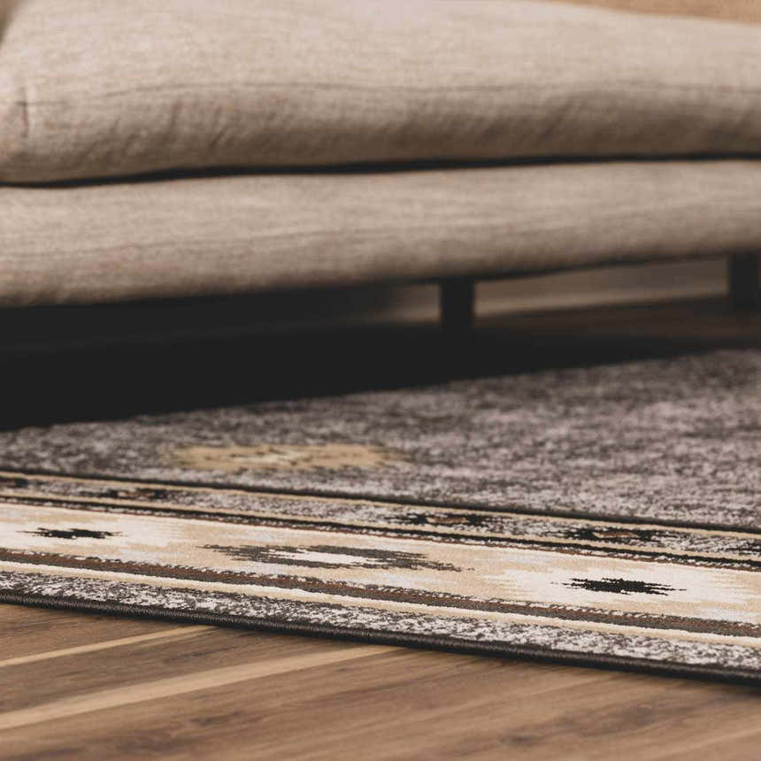 Close-up of the Buckhaven Area Rug showing its Southwestern-inspired pattern in black, charcoal, beige, and brown tones. Roomscene-Rectangle