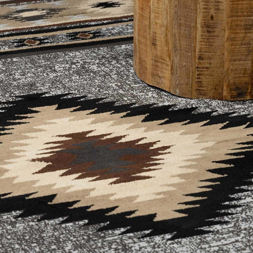 Close-up of the Buckhaven Area Rug showing its Southwestern-inspired geometric pattern in black, beige, brown, and gray. Styleshot