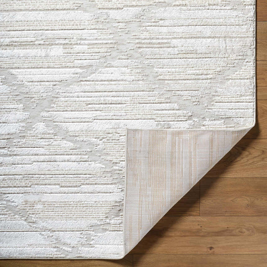 Close-up of the Akilah Area Rug showing its cream and ivory textured pattern and machine-woven construction. Fold