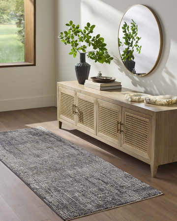 Entryway scene with a Southwestern Axelia Black Area Rug, wood console table, round mirror, and wood floors. Roomscene-Runner