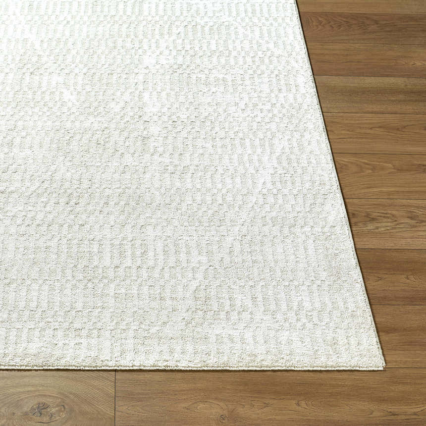 Close-up of the Pabla Cream Area Rug showing its ivory color and subtle geometric pattern on wood flooring. Front